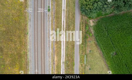 Vista aerea della ferrovia attraverso il paesaggio di campagna, prospettiva dall'alto verso il basso dal drone pov. Foto di alta qualità Foto Stock