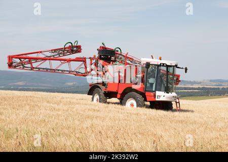 Un irroratore Bateman Crop che ripiega il suo braccio irroratore in un campo di Barley nella campagna scozzese Foto Stock