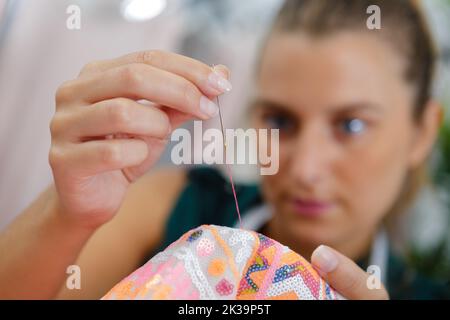 primo piano di donna cucire con ago e filo Foto Stock