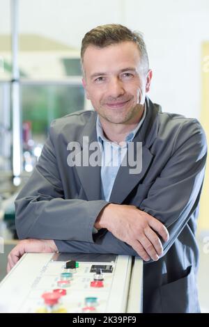 ritratto dell'uomo in fabbrica appoggiato sul pannello di controllo Foto Stock