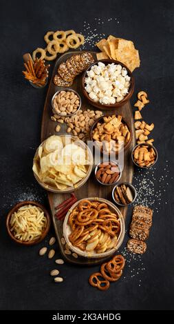 Assortimento di snack salati su sfondo scuro. Concetto di cibo per feste. Vista dall'alto Foto Stock