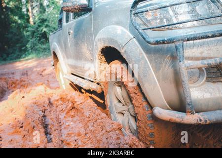 Pneumatici fuoristrada, auto fuoristrada sporca, SUV coperto di fango su strada di campagna. Fuoristrada e concetto di guida. Foto Stock