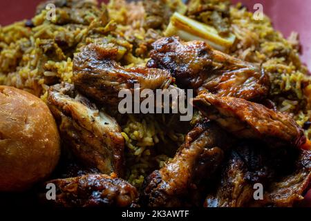 Ali di pollo giamaicano tradizionali, capra ricciata e gnocchi fritti con riso e piselli Foto Stock