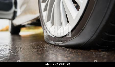 Vista ravvicinata dello pneumatico forato sulla ruota posteriore dell'automobile. Guasto, ruota danneggiata durante la guida su strada asfaltata. Che sfortuna, concetto di incidente. Foto Stock