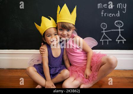 Crescere con grandi immaginazioni. Ritratto di due bambine che abbracciano mentre vestito come fate. Foto Stock