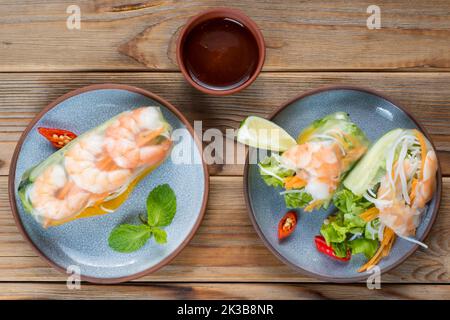 Vista di due involtini primavera vietnamiti con gamberi e lime su due piatti con salsa. Foto Stock