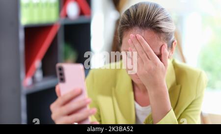 Giovane donna d'affari al telefono imbarazzata ricevendo sms con cattive notizie Foto Stock