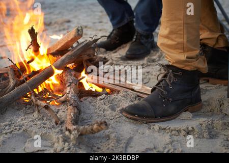 Quella era una notte fredda. Due giovani seduti attorno ad un fuoco sulla spiaggia. Foto Stock