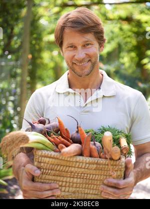 Thats a destra, il relativo completamente organico. Un uomo maturo che tiene in mano un cesto di verdure fresche. Foto Stock