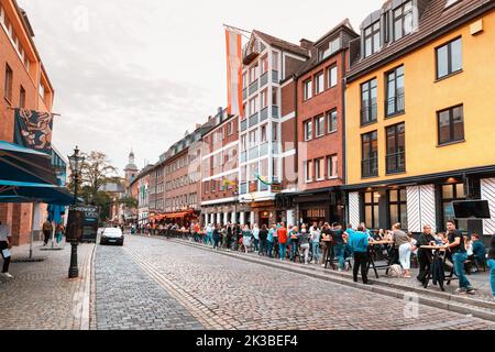 22 luglio 2022, Dusseldorf, Germania: Le persone riposano e si rilassano, bevono birra e mangiano spuntini nei pub e nei bar all'aperto nella vecchia strada della città Foto Stock