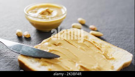 Immagine di primo piano del pane tostato con burro di arachidi su sfondo grigio Foto Stock