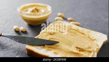 Immagine di primo piano del pane tostato con burro di arachidi su sfondo grigio Foto Stock