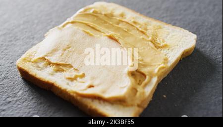 Immagine di primo piano del pane tostato con burro di arachidi su sfondo grigio Foto Stock