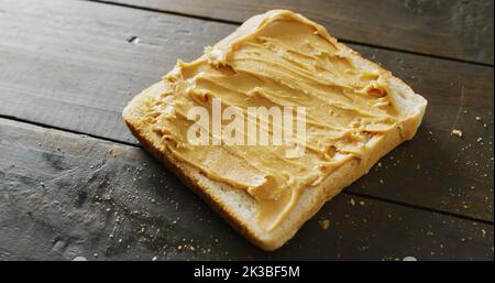 Immagine di primo piano di pane tostato con burro di arachidi su sfondo di legno Foto Stock