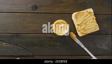 Immagine di primo piano di pane tostato con burro di arachidi su sfondo di legno Foto Stock