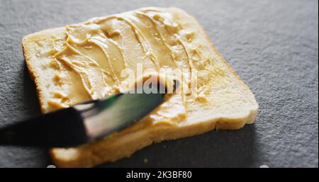 Immagine di primo piano del pane tostato con burro di arachidi su sfondo grigio Foto Stock