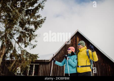 Coppia anziana in pausa durante lo sci, prossimo cottage foresta. Foto Stock