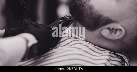 Barber taglia la barba di un uomo in un barbiere Foto Stock