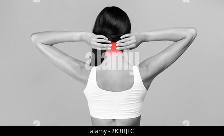 Vista posteriore della giovane donna che tocca la zona infiammata del collo, affetta da osteocondrosi cervicale Foto Stock
