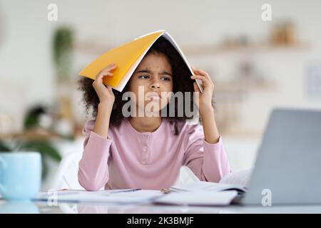 Arrabbiato ragazza nera scolaro facendo i compiti a casa Foto Stock