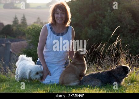 Donna felice sorridente con tre cani Foto Stock