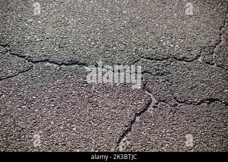 Struttura di primo piano di asfalto incrinato dalle temperature calde Foto Stock