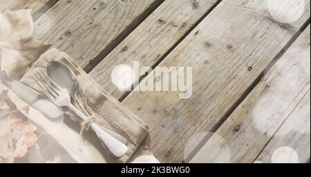 Immagine di macchie di luce su posate e foglie su sfondo di legno Foto Stock