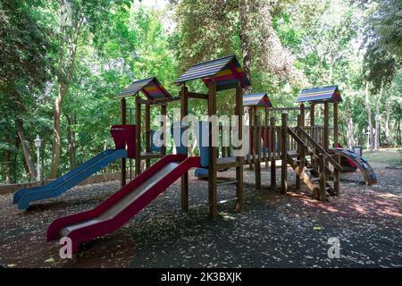Colorato parco giochi con scivoli nella foresta, campo giochi per bambini, parchi e all'aperto concetto, vuoto parco giochi con alberi sullo sfondo Foto Stock