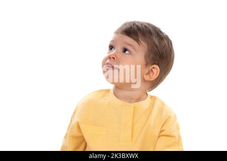 Bambino felice pensivo che guarda in su isolato su sfondo bianco Foto Stock