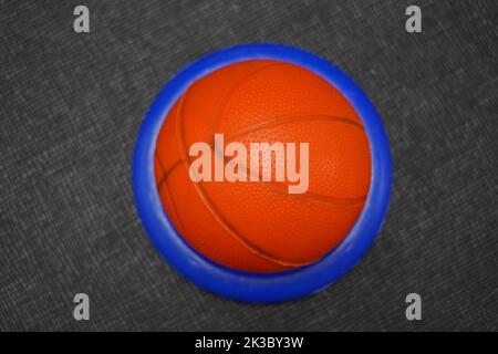 palla da basket giocattolo in anello di plastica blu su sfondo nero testurizzato Foto Stock