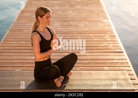 Bella donna rilassata con mani e occhi chiusi meditando all'aperto Foto Stock