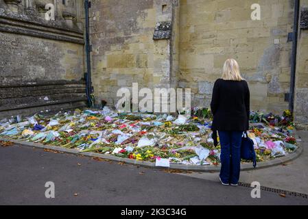 Donna che guarda i fiori deposti in tributo alla morte della defunto Regina Elisabetta II fuori dalla cattedrale di Salisbury, nel Wiltshire, Regno Unito Foto Stock