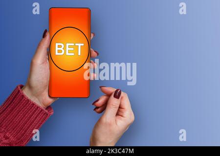 Casinò online. Una giovane donna fa scommesse in un gioco online, mentre una donna fa scommesse su uno smartphone Foto Stock