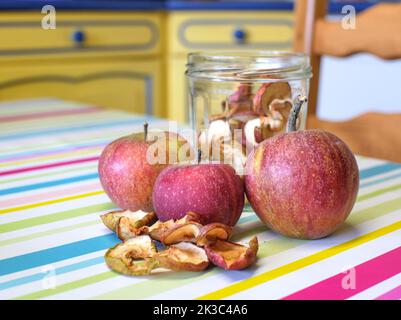 Mele secche e mele fresche poste su un asse di legno, su un tavolo da cucina Foto Stock