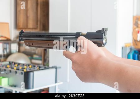 Vista ravvicinata delle mani di un ragazzo che tiene e punta una pistola pneumatica Foto Stock