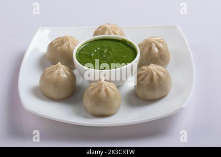 Vapore veic. Nepalese piatto tradizionale Momo farcito con verdure e poi cotto e servito con salsa su un rustico sfondo di legno, Foto Stock