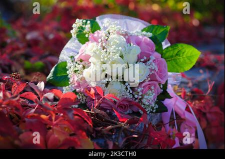 Bouquet nuziale di fiori con anelli dorati. Bouquet nuziale di rose rosa e bianche adagiate su un prato Foto Stock