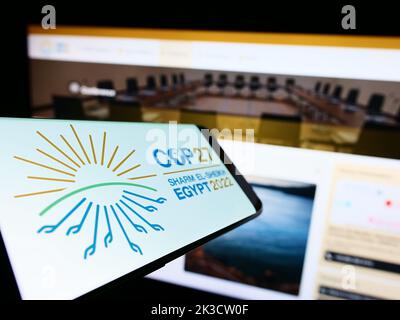 Smartphone con il logo della 2022 Conferenza ONU sul cambiamento climatico (COP27) sullo schermo di fronte al sito Web. Messa a fuoco al centro a sinistra del display del telefono. Foto Stock