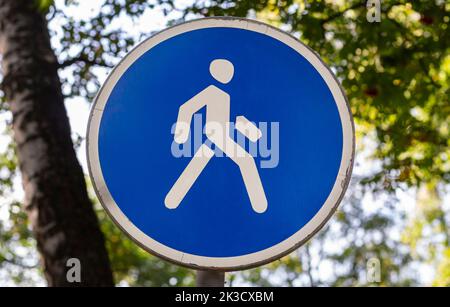 Cartello stradale rotondo blu con icona umana bianca, messa a fuoco selettiva con spazio copia. Zona pedonale nel cartello stradale del parco. Concetto di controllo e regolazione del traffico Foto Stock