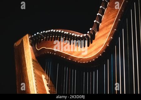 Primo piano del dettaglio di un collo e ponte di arpa con finiture in legno naturale celtico con piedini e corde Foto Stock