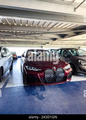 Basilea, Svizzera - 22 settembre 2022: Vista frontale della nuova vettura di lusso BMW Serie 4 Gran Coupe parcheggiata in un ampio parcheggio aeroportuale - bellissimo colore rosso scuro Foto Stock