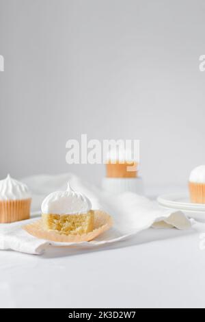 Cupcake alla vaniglia con una glassa di meringa, cupcake con un boccone estratto, glassa bianca sulla torta Foto Stock