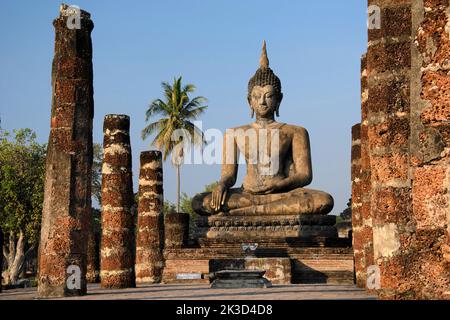 Statua del Buddha seduto all'alba nel tempio di Wat Mahathat, parco storico di Sukhothai, patrimonio dell'umanità dell'UNESCO, Thailandia settentrionale. Foto Stock