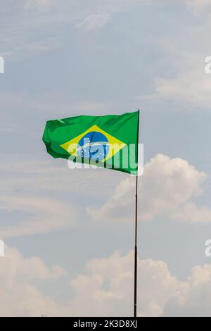 Goiânia, Goias, Brasile – 25 settembre 2022: Bandiera del Brasile che vola e che sbatte nel vento con cielo nuvoloso sullo sfondo. Foto Stock