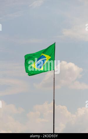 Goiânia, Goias, Brasile – 25 settembre 2022: Bandiera del Brasile che vola e che sbatte nel vento con cielo nuvoloso sullo sfondo. Foto Stock