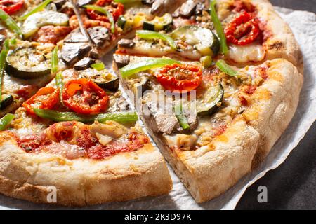 Pizza vegetariana con zucchine, pomodoro, peperoni e funghi su tavola di legno. Primo piano Foto Stock