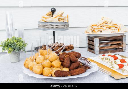 Tavolo servito con panini al formaggio, patate ripiene, crocchette di maiale e Kipes dominicani. Foto Stock