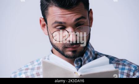 pensierd studente in eyeglasses lettura libro isolato su grigio, immagine stock Foto Stock