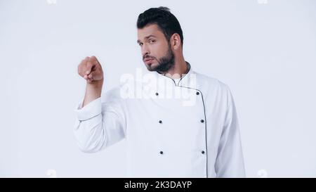 giovane chef guardando la macchina fotografica mentre condimento qualcosa isolato su bianco, immagine stock Foto Stock