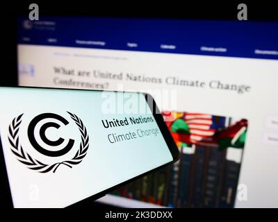 Cellulare con il logo del trattato ambientale delle Nazioni Unite UNFCCC sullo schermo di fronte al sito web. Messa a fuoco al centro a sinistra del display del telefono. Foto Stock